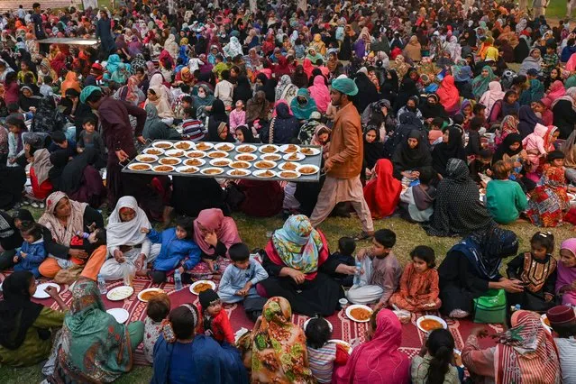 Volunteers distribute free food as Muslim devotees gather to break their fast during the Islamic holy month of Ramadan in Lahore on March 13, 2024. (Photo by Arif Ali/AFP Photo)