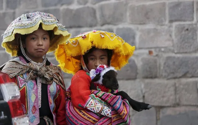 Children walk as one of them carries a lamb near Peru's presidential candidate Veronika Mendoza campaign headquarters in Cuzco, Peru, April 10, 2016. (Photo by Janine Costa/Reuters)