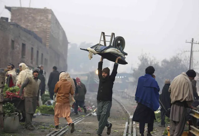 A man carries a handcart over his head at a market in Peshawar, Pakistan, Wednesday, December 22, 2021. (Photo by Mohammad Sajjad/AP Photo)