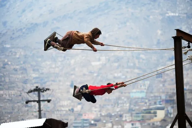 Afghan boys take flight on swings at a fair set up in a field near the Sahki Shrine during Nowruz festivities which marks the Afghan New Year in Kabul on March 21, 2014. Nowruz, one of the biggest festivals of the war-scarred nation, marks the first day of spring and the beginning of the year in the Persian calendar. Parents with their children celebrate the New Year by participating in the fair set up near the shrine. (Photo by Roberto Schmidt/AFP Photo)