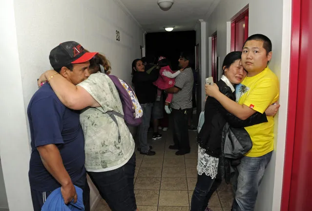 People embrace on the upper floor of an apartment building located a few blocks from the coast where they gathered to avoid a possible tsunami after an earthquake in Iquique, Chile, Tuesday, April 1, 2014. A powerful magnitude-8.2 earthquake struck off Chile's northern coast Tuesday night. There were no immediate reports of injuries or major damage, but buildings shook in nearby Peru and in Bolivia's high altitude capital of La Paz. (Photo by Cristian Viveros/AP Photo)