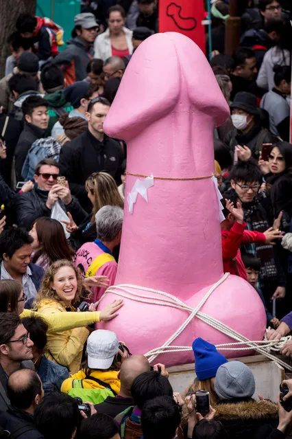 People pose for photos in front of a large pink phallic-shaped “Mikoshi” during Kanamara Matsuri (Festival of the Steel Phallus) on April 6, 2014 in Kawasaki, Japan. The Kanamara Festival is held annually on the first Sunday of April. (Photo by Chris McGrath/Getty Images)