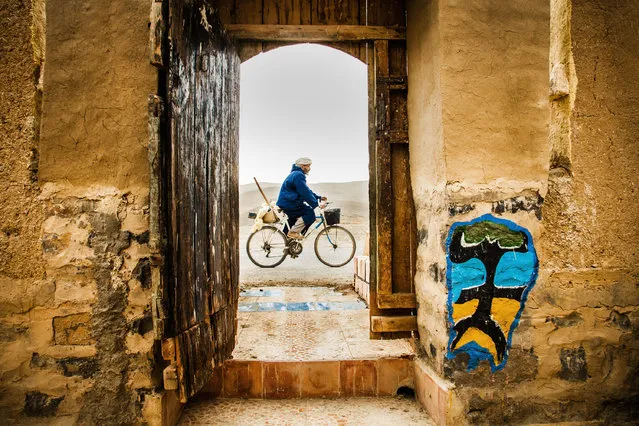 “Cycling in Morrocco”. This picture is taken in the Central Atlas Mountains, Morocco. This area is populated by the idigenous Berber inhabitants. The sign on the wall represents the Berber, Tamazigh-flag. Tamazigh is the local language. The name also stands for: free man, noble man. Photo location: Agoudal, Central Atlas Mountains, Morocco. (Photo and caption by Hielke Gerritse/National Geographic Photo Contest)