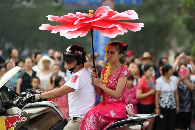 A woman takes part in a parade to celebrate the Dai ethnic group new year in Jinghong, southwest China's Yunnan province on April 14, 2014. A series of celebrations kick off on April 13 to welcome the coming year of 1376 in the Dai ethnic group calendar, with people dancing and parading on the streets of Jinghong municipality in China's Xishuangbanna Dai Autonomous Prefecture. (Photo by AFP Photo)