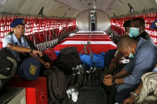 Relatives sit beside the coffins of the victims of an Indonesian military C-130B Hercules aircraft that crashed into a residential area, inside a CN235 air force plane before heading to Jakarta, at a military airbase in Medan, North Sumatra province, Indonesia, July 1, 2015. Indonesia's president promised a review of the country's ageing air force fleet and a defence modernisation drive on Wednesday. (Photo by Reuters/Beawiharta)