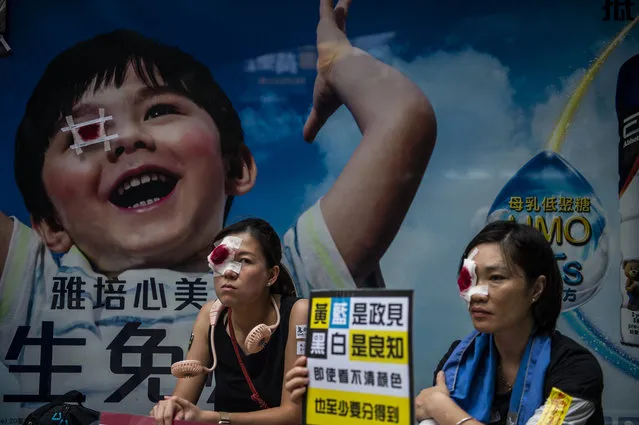 Protester with their left eyes covered in a red bandage sit next to a commercial billboard which the child in it had has his left eye covered with a bandage in Hong Kong on August 18, 2019, Tens of Thousands take to the streets of Hong Kong in a rally in Victoria Park – According to the organizers over 1.7 million people attended the rally , Hong Kong has been rocked by weeks of protest. (Photo by Vernon Yuen/NurPhoto via Getty Images)