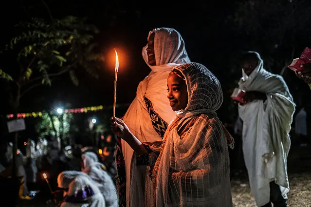An Ethiopian Orthodox child holds a candle in the compound of Fasilides Bath during the celebration of Timkat, the Ethiopian Epiphany, in the city of Gondar, Ethiopia, on January 19, 2022. (Photo by Eduardo Soteras/AFP Photo)