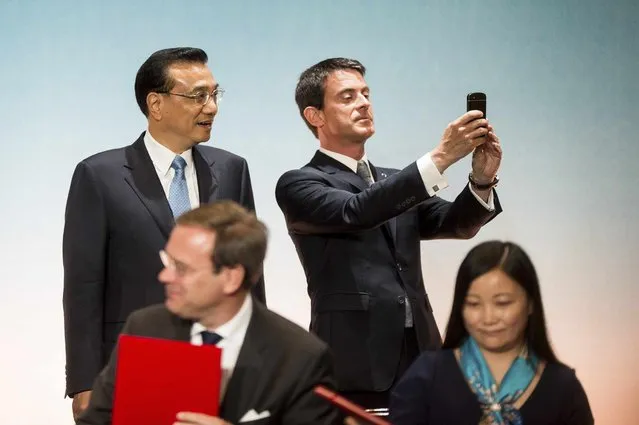 French Prime Minister Manuel Valls (R) takes a picture with his mobile phone as Chinese Premier Li Keqiang looks on during a Franco-Chinese Economic Summit in Toulouse, southwestern France, July 2, 2015. (Photo by Fred Lancelot/Reuters)