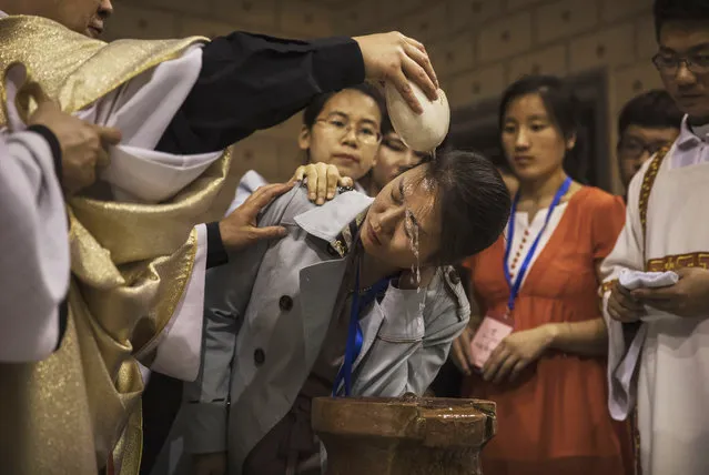 Chinese Catholic Bishop Zhang Hong, left, pours holy water on the head of a worshipper during a special baptism ceremony at a mass on Holy Saturday during Easter celebrations at the government sanctioned West Beijing Catholic Church on April 15, 2017 in Beijing, China. China, an officially atheist country, places a number of restrictions on Christians, allowing legal practice of the faith only at state-approved churches. The policy has driven an increasing number of Christians and Christian converts 'underground' to congregations in private homes and other venues.  While the size of the religious community is difficult to measure, studies estimate there are more than 80 million Christians inside China; some studies support the possibility it could become the most Christian nation in the world in the coming years. Officially there have been no relations between China and the Vatican since the country's modern founding in 1949 though in recent years there have been signs of warming relations between Chinese president Xi Jinping and Pope Francis that could possibly allow greater religious freedom in the future. At present, the split means approved Chinese Christians worship within a state-sanctioned Church known as the Patriotic Association which regards the Communist Party as its leader, not the Pope in Rome. (Photo by Kevin Frayer/Getty Images)