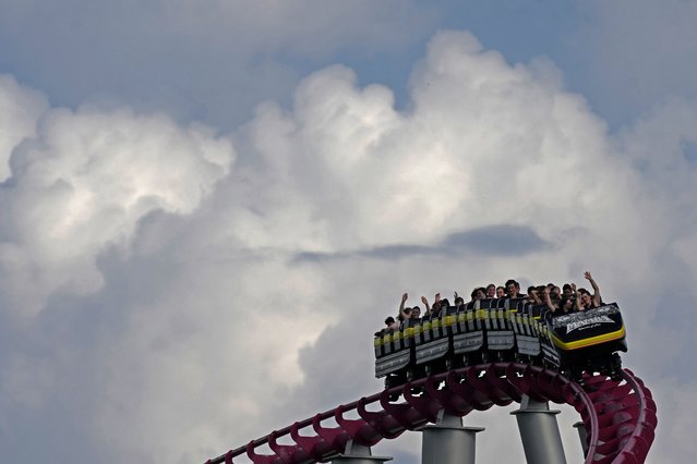 People ride on the Mamba roller coaster at Worlds of Fun theme park as storm clouds build in the distance on the first full day of summer Friday, June 21, 2024, in Kansas City, Mo. (Photo by Charlie Riedel/AP Photo)