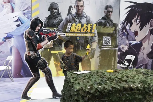 A child plays with a toy gun during a promotion for online games in Beijing on Saturday, August 29, 2020. China is banning children from playing online games for more than three hours a week, the harshest restriction so far on the game industry as Chinese regulators continue cracking down on the technology sector. (Photo by Ng Han Guan/AP Photo)