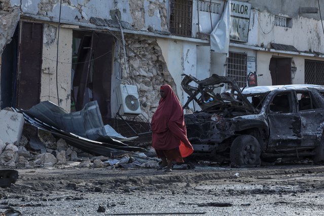 A woman walks past debris and destruction at a cafe in Mogadishu on July 15, 2024 following a car bomb blast where five people were killed where football fans were watching the Euro 2024 final late on July 14, 2024. (Photo by Hassan Ali Elmi/AFP Photo)