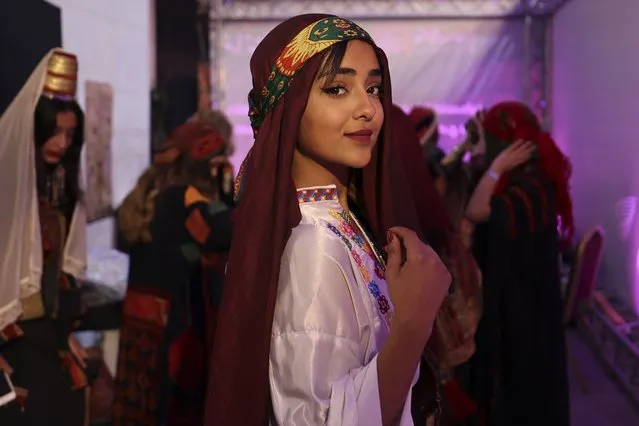 A Palestinianwoman, wearing a traditional embroidered dress, poses for a picture during  an event celebrating the registration of Palestinian embroidery on the UNESCO Cultural Heritage List, in the West Bank city of Ramallah on March 9, 2022. (Photo by Abbas Momani/AFP Photo)
