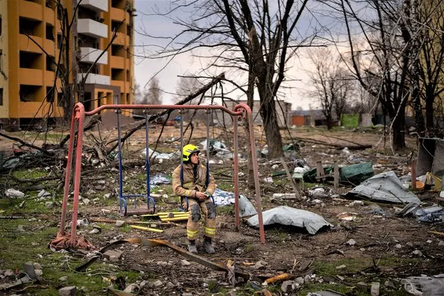 A firefighter sits on a swing next to a building destroyed by a Russian bomb in Chernihiv on Friday, April 22, 2022. (Photo by Emilio Morenatti/AP Photo)