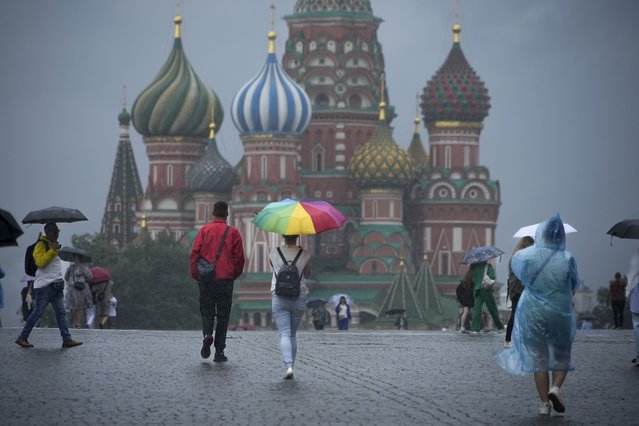 People with umbrellas walk through Red Square under rain in Moscow, Russia, Monday, July 22, 2024. After hot weather, the temperature in Moscow dropped to 22 Celsius, (71,6 Fahrenheit). (Photo by Alexander Zemlianichenko/AP Photo)