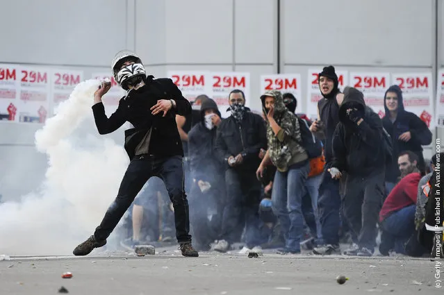A demonstrator throws back a teargas canister during heavy clashes with riot police during a 24-hour strike on March 29, 2012 in Barcelona, Spain