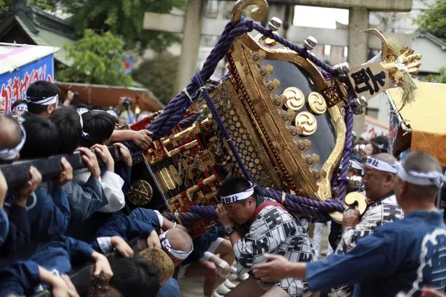 Participants clad in traditional “happi” coats carry and strongly swing “mikoshi”, or portable shrine to left and right in Tenno-sai festival at Susanoo Shrine in Tokyo Saturday, June 4, 2016. Tenno-sai festival is an annual traditional festival which is believed to expel a contagious disease in summer to protect people. (Photo by Eugene Hoshiko/AP Photo)