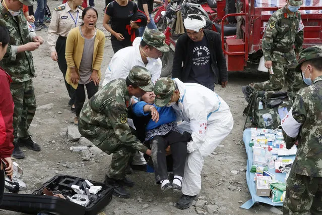 An elderly woman faints upon seeing the bodies of her dead relatives at the site of a landslide in Xinmo village in Maoxian County in southwestern China's Sichuan Province, Sunday, June 25, 2017. (Photo by Ng Han Guan/AP Photo)