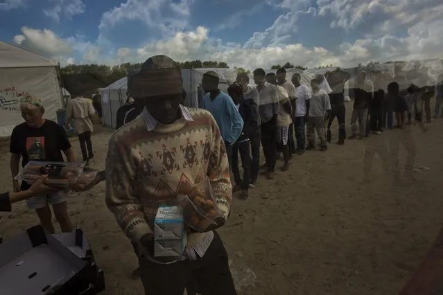 Migrants receive their food rations distributed by the Banque Alimentaire of Calais at a camp in northern France, Tuesday, August 4, 2015. The European Union is offering funds and aid to help France cope with growing numbers of migrants near the northern city of Calais. It comes as thousands of migrants have been scaling fences near the Channel Tunnel linking the two countries and boarding freight trains or trucks destined for Britain. (Photo by Emilio Morenatti/AP Photo)