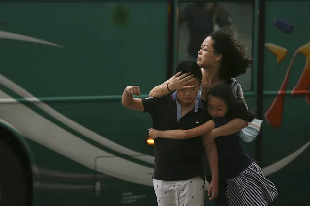 A mother holds her children in strong gusts from Typhoon Soudelor in Taipei, Taiwan, Friday, August 8, 2015. (Photo by Wally Santana/AP Photo)