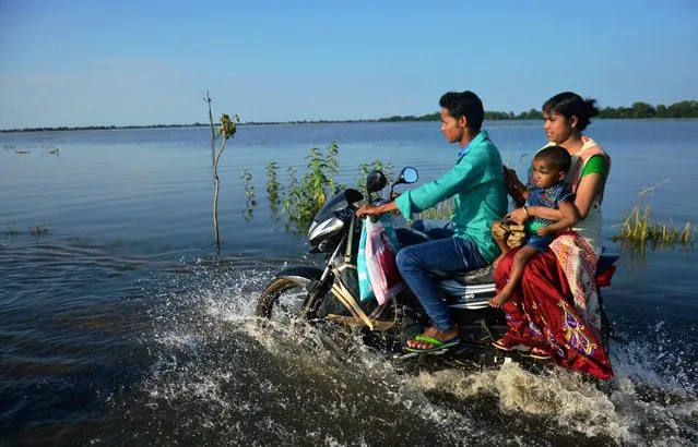 A family travel on bike wade through a flooded road at Jamlai village in Kamrup district, Assam on Thursday, July 14, 2017. The flood situation in the state has turned grave with the 17,43,119 people in 2,450 villages of 26 districts reeling under flood during the past 24 hours. (Photo by Press Trust of India Photo)