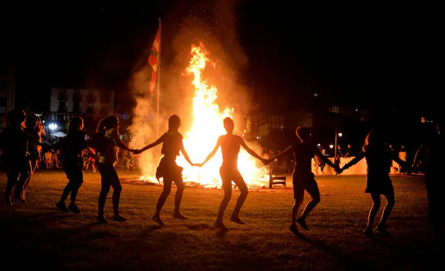 Women dance around a bonfire during the traditional San Juan's (Saint John) night in the Basque coastal town of Mundaka, northern Spain, June 24, 2016. (Photo by Vincent West/Reuters)
