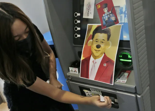 A protester attaches stickers and a defaced portrait of Chinese President Xi Jinping on a Bank of China's ATM machine during an anti-government rally at Hong Kong University of Science and Technology in Hong Kong, Thursday, November 7, 2019. (Photo by Dita Alangkara/AP Photo)