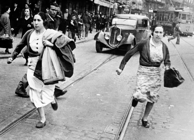 Civilians scurry for shelter through the streets of Bilbao, northern Spain, during an air raid, June 15, 1937. (Photo by AP Photo)