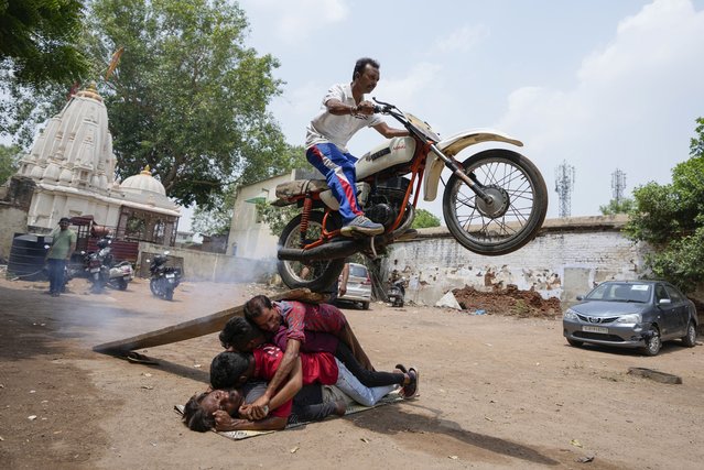 Indian youth practice a bike stunt ahead of a procession marking the annual Rath Yatra or chariot festival of Hindu deity Lord Jagannath in Ahmedabad, India, Wednesday, June 22, 2022. The festival is scheduled to be celebrated on July 1, 2022. (Photo by Ajit Solanki/AP Photo)