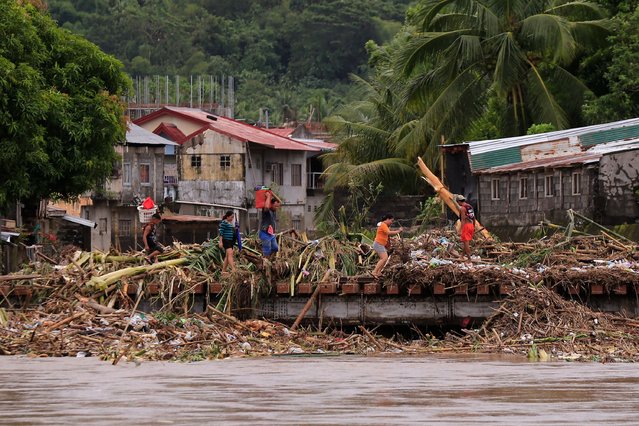 Residents cross a bridge filled with debris due to heavy rains brought about by Tropical Storm Trami in Polangui town, Albay province South of Manila on October 23, 2024. (Photo by Charism Sayat/AFP Photo)