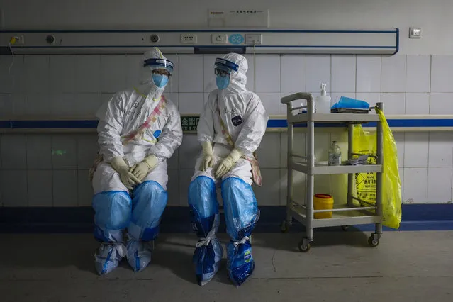 In this Sunday, February 16, 2020, photo, medical workers wearing full protective suits chat to each other at a hospital in Wuhan in central China's Hubei province. Chinese authorities on Monday reported a slight upturn in new virus cases and hundred more deaths for a total of thousands since the outbreak began two months ago. (Photo by Chinatopix via AP Photo)