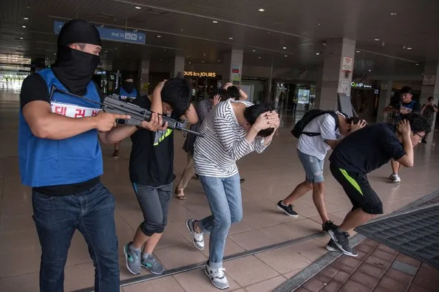 People enact a mock hostage situation during an anti-terror drill in Goyang on August 21, 2017. Meanwhile tens of thousands of South Korean and US troops are taking part in the “Ulchi Freedom Guardian” joint military drills, a largely computer-simulated exercise that runs for two weeks in the South. (Photo by Ed Jones/AFP Photo)
