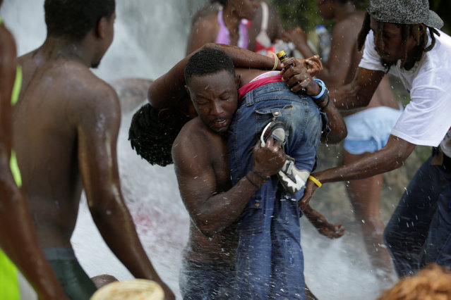 A man carries a woman who fainted during the celebration of the annual pilgrimage to the waterfall in Saut D'Eau, Haiti, July 16, 2016. (Photo by Andres Martinez Casares/Reuters)