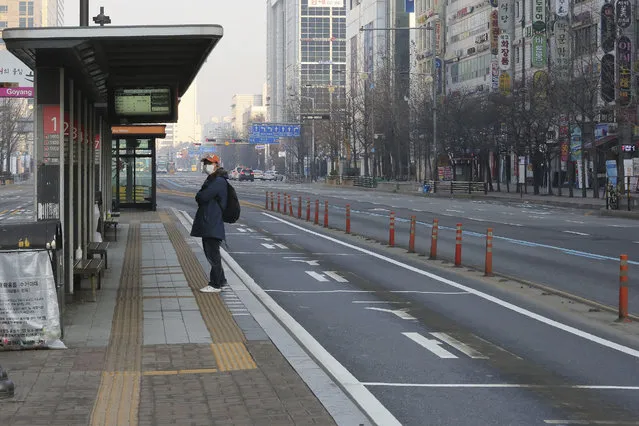 A man wearing a face mask waits for the bus at a stop in Goyang, South Korea, Sunday, March 8, 2020. The number of infections of the COVID-19 disease spread around the globe. (Photo by Ahn Young-joon/AP Photo)