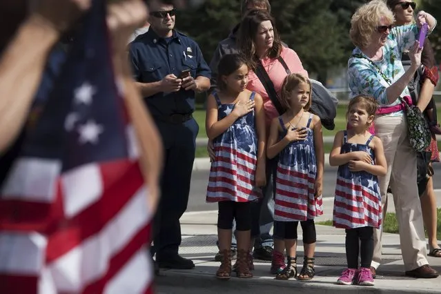 Crowds watch a procession of emergency service vehicles during a memorial for U.S. Forest Service firefighters Tom Zbyszewski, Andrew Zajac, and Richard Wheeler, who died fighting the Okanogan Complex fire, in Wenatchee, Washington, August 30, 2015. So far this year, U.S. wildland blazes have claimed the lives of at least 13 firefighters, four more than were killed in the line of duty during all of 2014. (Photo by David Ryder/Reuters)