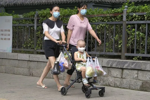 Residents carry their fresh produces after shopping in Beijing, Monday, August 15, 2022. (Photo by Ng Han Guan/AP Photo)
