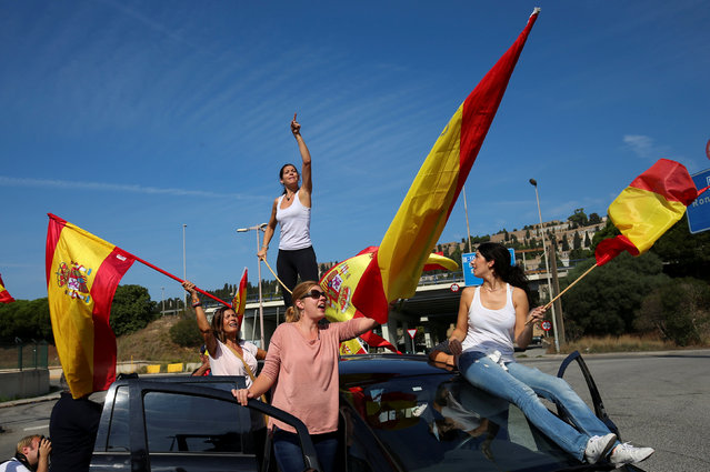 People wave Spanish flags as they gather at port to try to give supplies to Spanish National Police and Guardia Civil officers, who are housing in ferry boats, in Barcelona, Spain, September 24, 2017. (Photo by Albert Gea/Reuters)