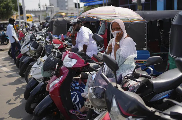 A woman waits to fill gas in her scooter at a fuel station in Colombo, Sri Lanka, Wednesday, July 27, 2022. (Photo by Eranga Jayawardena/AP Photo)