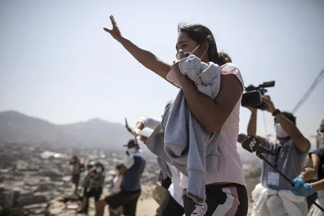 From the top of a hill, a woman shouts at a relative who is an inmate at the Lurigancho prison during a prison protest, in Lima, Peru, Tuesday, April 28, 2020. Inmates complain that authorities are not doing enough to prevent the spread of the new coronavirus inside the prison. (Photo by Rodrigo Abd/AP Photo)