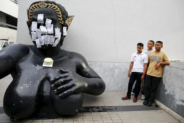 Plainclothes policemen stand next to a statue after students supporting the opposition attached mock ballots with option “No” selected to it during a protest against the military-backed draft constitution in Bangkok, Thailand September 5, 2015. (Photo by Jorge Silva/Reuters)
