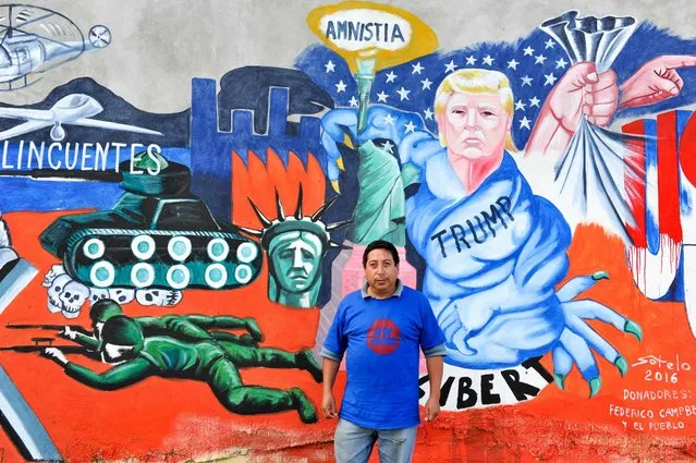 Mexican artist Luis Sotelo poses in front of his worh, a mural paint called “We are migrants not criminals” (Somos migrantes no delincuentes) in Tonatico, Mexico, on 25 June 2016. The mural is part of the cultural movement “Stop Trump”. (Photo by Mario Vazquez/AFP Photo)