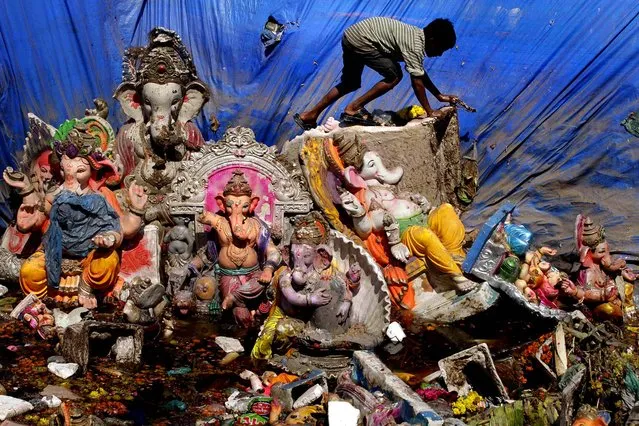 A boy searches for reusable items amid idols of the Hindu  god Ganesh left a day after the immersion of idols in Ahmadabad, India, on September 30, 2012. Every year millions of devout Hindus immerse Ganesh idols into oceans and rivers during the ten-day long Ganesh Chaturthi festival that celebrates the birth of the Hindu god. (Photo by Ajit Solanki/Associated Press)