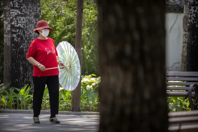 A woman wearing a face mask to protect against the new coronavirus dances with a parasol at a public park in Beijing, Wednesday, June 10, 2020. China says its three latest cases of coronavirus infection were brought from outside the country. No new deaths were reported Wednesday and just a few dozen people remain in treatment for COVID-19. (Photo by Mark Schiefelbein/AP Photo)
