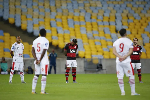 Players of Bangu, wearing white uniforms, and Flamengo pay a minute of silence for the victims of the coronavirus prior to a Rio de Janeiro soccer league match at the Maracana stadium in Rio de Janeiro, Brazi, Thursday, June 18, 2020. Rio de Janeiro's soccer league resumed after a three-month hiatus because of the coronavirus pandemic. The match is being played without spectators to curb the spread of COVID-19. (Photo by Leo Correa/AP Photo)