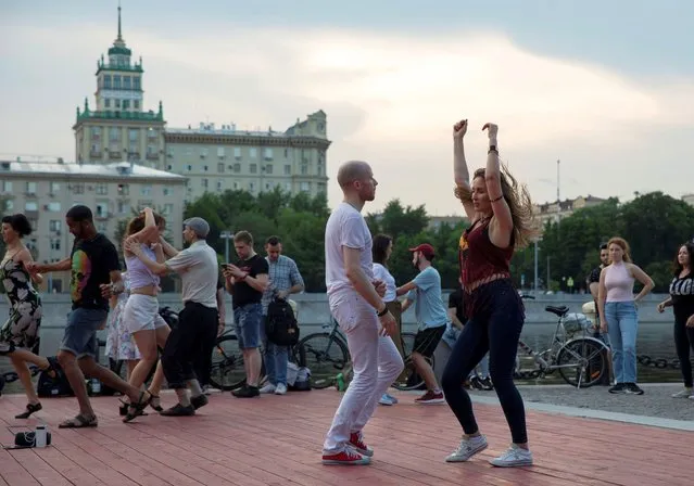 People dance on the first day that lockdown measures were eased at an embankment over the Moscow River in Moscow, Russia, Tuesday, June 9, 2020. The Russian capital on Tuesday has ended a tight lockdown in place since late March, citing a slowdown in the coronavirus outbreak. Starting from Tuesday, Moscow residents are no longer required to self-isolate at home or obtain electronic passes for traveling around the city. (Photo by Pavel Golovkin/AP Photo)