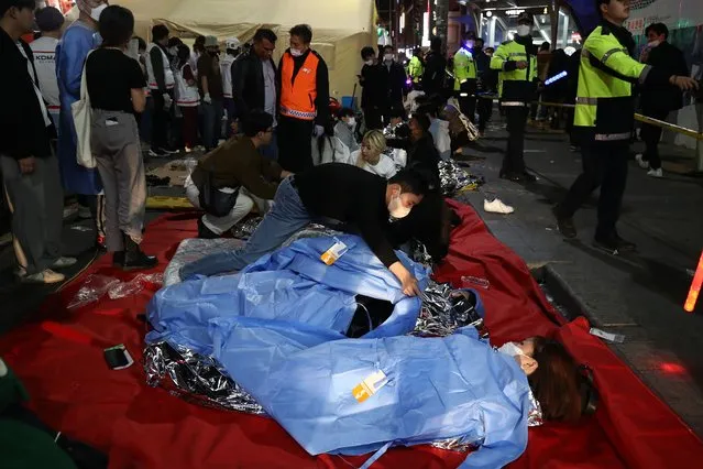 Emergency services treat injured people after a stampede on October 30, 2022 in Seoul, South Korea. At least 50 people were reported to be receiving CPR after suffering from cardiac arrest in Seoul's Itaewon area as huge crowds of people stampeded at Halloween parties, according to authorities. (Photo by Chung Sung-Jun/Getty Images)