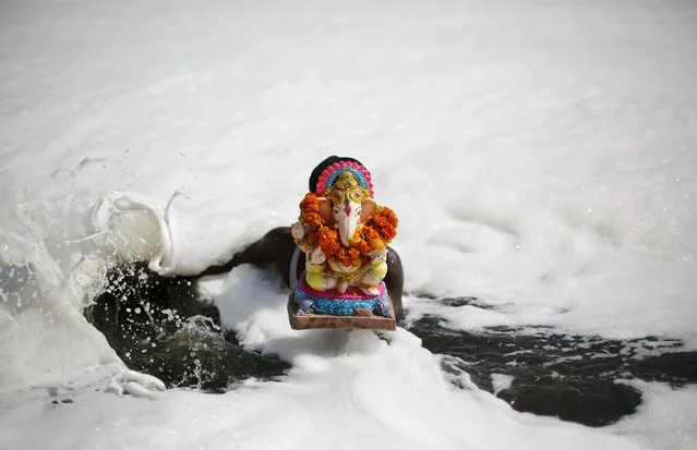 A devotee carries a statue of the Hindu god Ganesh, the deity of prosperity, to be immersed into the polluted waters of the river Yamuna on the last day of the Ganesh Chaturthi festival, in New Delhi, India, September 27, 2015. (Photo by Adnan Abidi/Reuters)