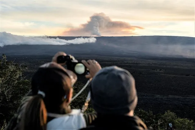 A person uses binoculars to take a photo with a smartphone during the eruption of the Mauna Loa Volcano in Hawaii, U.S. December 1, 2022. (Photo by Go Nakamura/Reuters)