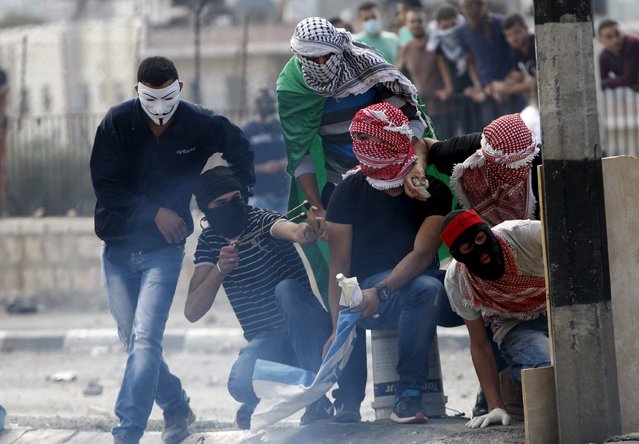 Palestinian stone-throwers take cover during clashes with Israeli troops in the occupied West Bank city of Bethlehem October 6, 2015. Palestinian President Mahmoud Abbas said on Tuesday he did not want a spike in deadly violence in East Jerusalem and the Israeli-occupied West Bank to spiral into armed confrontation with Israel. (Photo by Mussa Qawasma/Reuters)