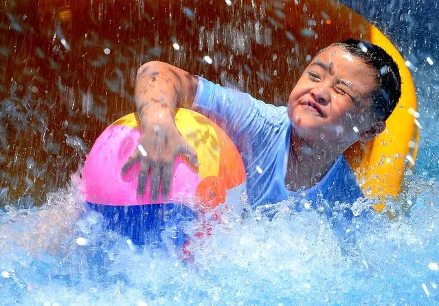 A boy plays at a water playground in downtown Taipei amid a wave of simmering summer heat. (Photo by Patrick Lin/AFP Photo)